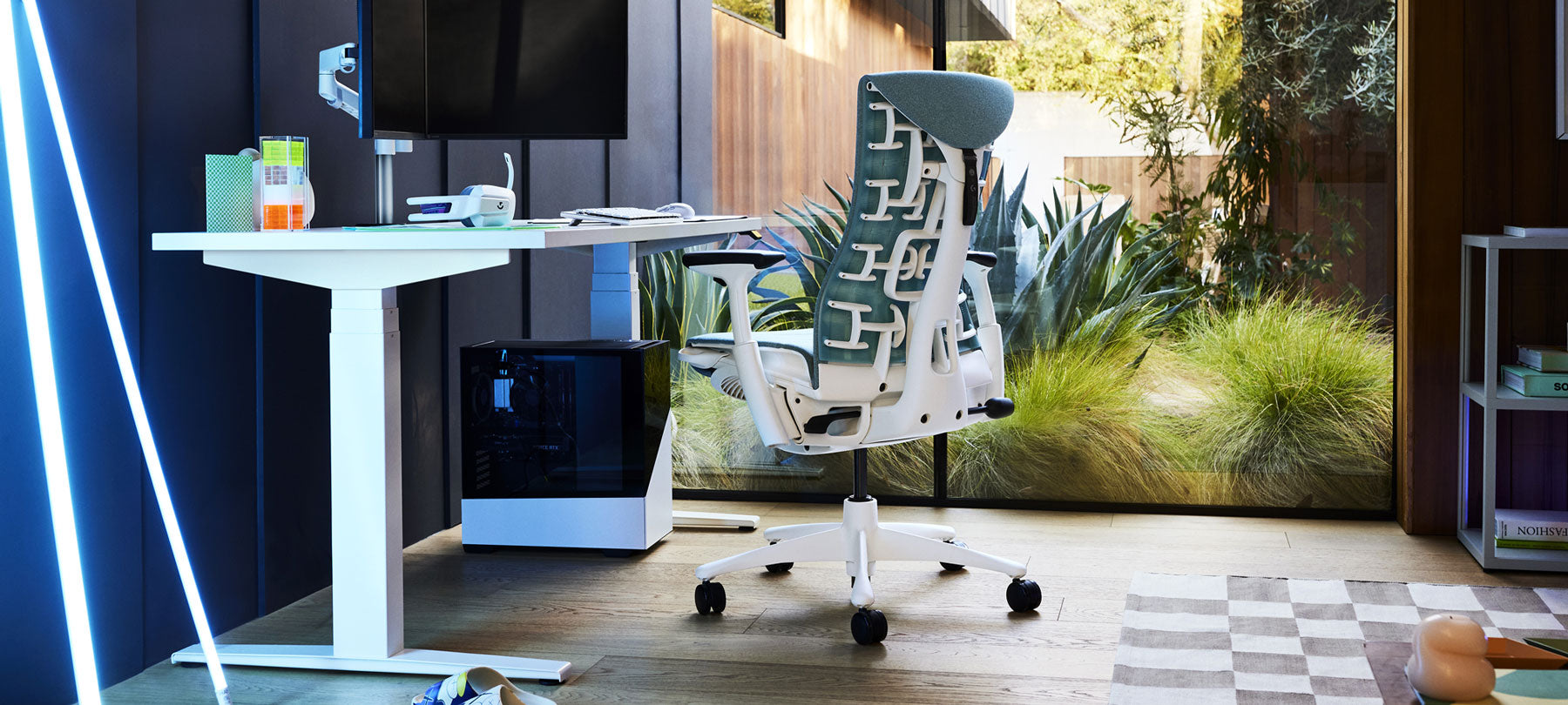 Una configuración de juego con una silla Embody de Herman Miller verde Galaxy, un escritorio Nevi blanco y un brazo de monitor doble Lima.